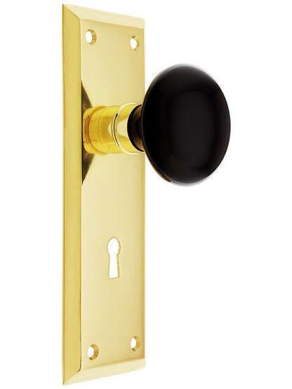 New York Style Door Set with Black Porcelain Knobs with Keyhole in Unlacquered Brass.
